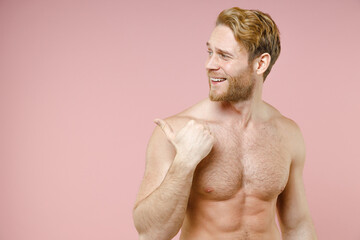 Fototapeta premium Handsome smiling bearded naked young man 20s years old perfect skin pointing thumb aside isolated on pastel pink color background studio portrait. Skin care healthcare cosmetic procedures concept.