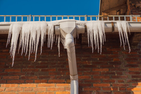 gef&auml;hrliche Eiszapfen an Haus und Dachrinne im Winter gefroren zu Eis
