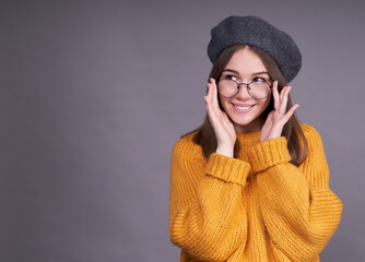 Pleasant sweet young girl adjusts glasses on her face.