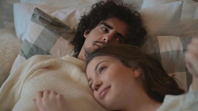 Valentine's Day. Close-up of young romantic cute couple lying in bed talking in love and wearing winter clothes.