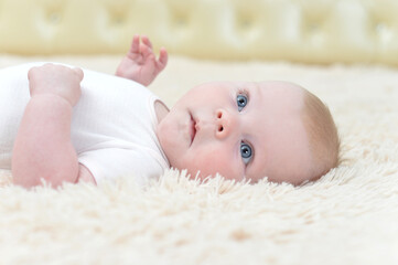 little baby girl lying on fluffy blanket and looking at the camera