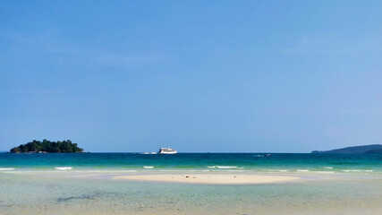 An empty beach with white sand and waves. Islands and boats in the distance. 4K Beach. Koh Rong island.  Cambodia. South-East Asia