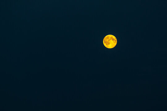 Full moon glowing with well-available craters over black sky