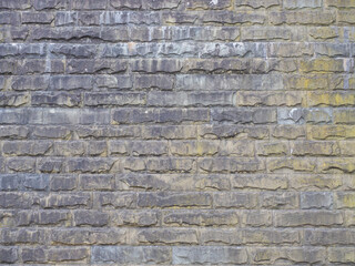 Wall with rough textured masonry covered with stains and darkened. Not seamless texture