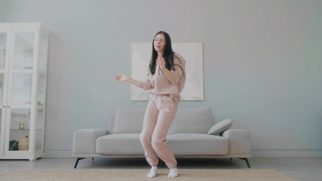 Young funny caucasian woman with glasses joyfully dancing and at home.
