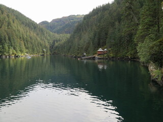 the view of a bay with a wooden house on a boat cruise somewhere in the Kenai Fjords, Kenai Peninsula Borough, close to Seward, Alaska, USA, September