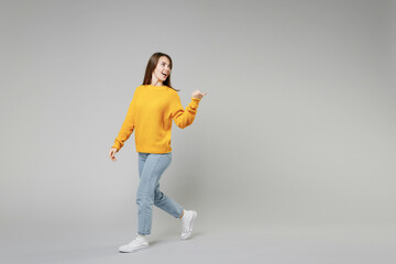 Full length of young smiling positive caucasian happy woman 20s in knitted yellow sweater walk...