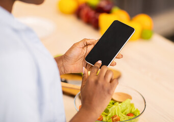 Black Woman Using Phone With Blank Screen In Kitchen, Cropped