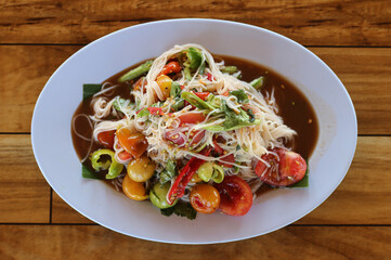 Papaya salad with noodles in the plate on table.