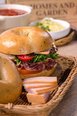 Hams with set of Fresh healthy bagel sandwich with ham, salami, tomatoes and vegetable in basket on wooden table