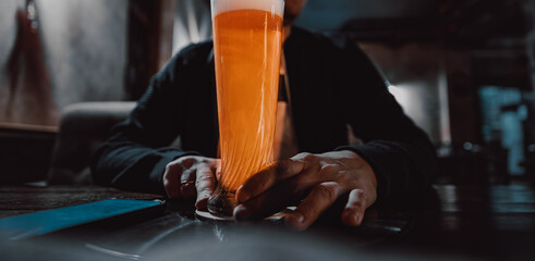 man holds a glass of beer in his hand at the bar or pub