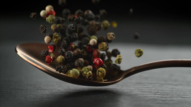 Colorful Pepper Blend on Copper Tablespoon Falling onto Stone Tabletop in Slow Motion (Phantom Flex)
