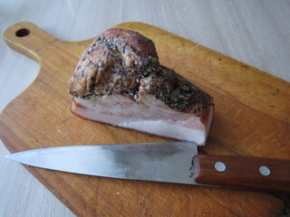 Smoked bacon with spices on a wooden cutting board