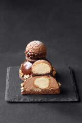 Contemporary Chocolate Mousse Cake with Craquelin Choux Pastry, covered with chocolate mirror glaze, on a dark background.