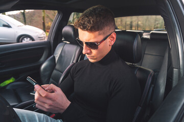 Young caucasian man inside a car using a smartphone
