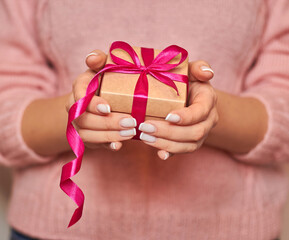woman holds a beautiful red gift box in her hand. Women's hands with a gift on a light background. March 8. February 14. Mother's Day. Valentine's Day.