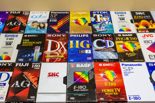 Colorful plastic and paper cases with VHS videotapes.