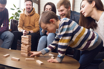 Child with parents playing board games, fun time at home with family and friends