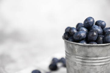 Closeup of Fresh blueberries in a small metal bucket. TSide view. Rustic.