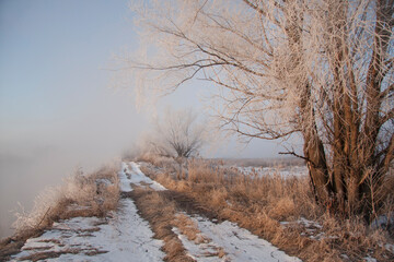 Spring landscape with a river covered with fog, melting snow on the river bank, trees