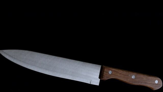 Kitchen Knife Spinning Around and Falling down on Black Background 