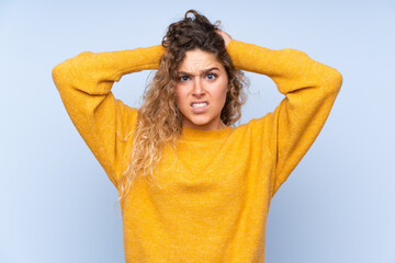 Fototapeta na wymiar Young blonde woman with curly hair isolated on blue background frustrated and takes hands on head