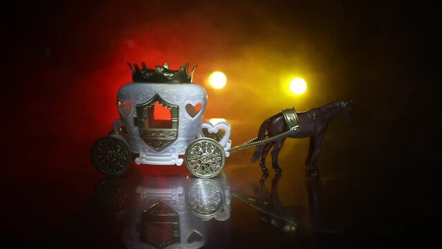 Little carriage with horse miniature on table. Creative decoration on dark toned foggy background. Selective focus