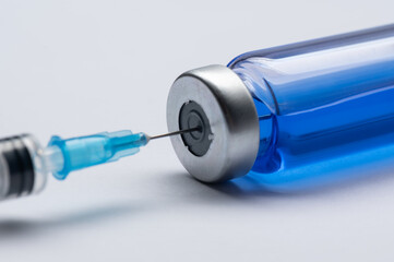 Covid19 Vaccine bottle with a blue liquid and taking the vaccine from it with a syringe. Several bottles of vaccine are lying side by side. Coronavirus vaccination concept.