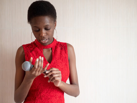 African american woman in red dress singing karaoke with microphone