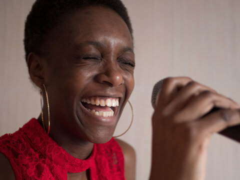 African american woman in red dress singing karaoke with microphone smile