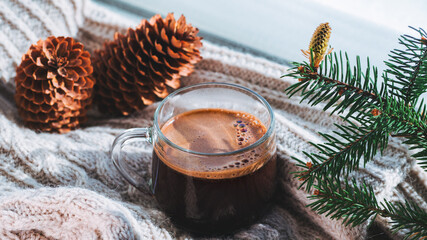Glass cup of hot espresso coffee, soft knitted warm scarf on the windowsill, winter time. Home comfort and hygge style