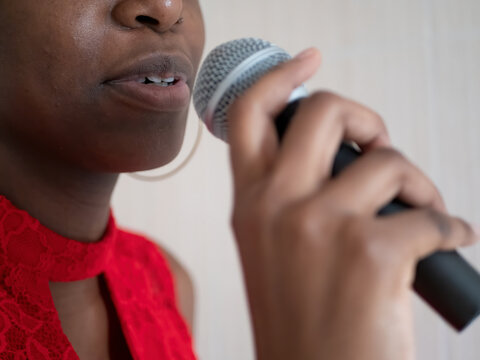 African american woman in red dress singing karaoke with microphone shallow depth of field