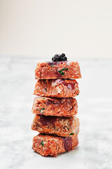 Composition with raw square cutlets on light background. Natural food for dogs. BARF dog diet