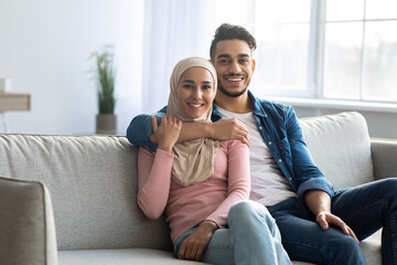 Obraz premium Positive arab couple posing on couch at home