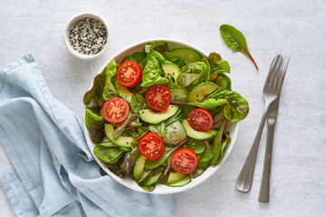 Vegan salad with tomatoes, cucumbers, avocado on pastel gray concrete table. Vegeterian mediterranean food, low calories dieting meal