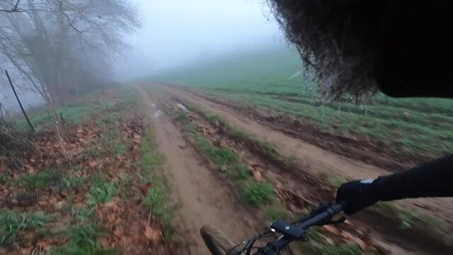 Riding a mountain bike on a muddy gravel path on a green foggy landscape