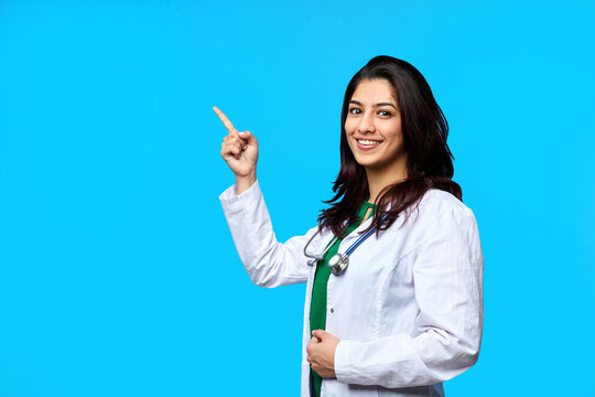 Beautiful Asian Doctor Lady pointing with hand on copy space, studio shot. Isolated on a gray background. Medical student general practitioner