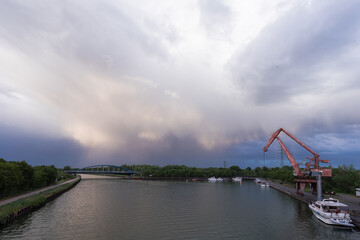 painting a rainbow in the blue sky above the river port with an old crane