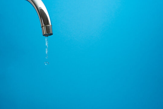 water coming out of a tap on blue background. Whith copyspace