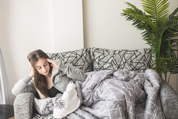 Sick woman lying on sofa in her home with high fever. She is hold the head with her hand.