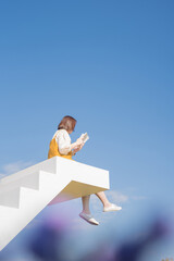 Fototapeta na wymiar asian woman relax and reading on white stair in flower garden on springtime vacation