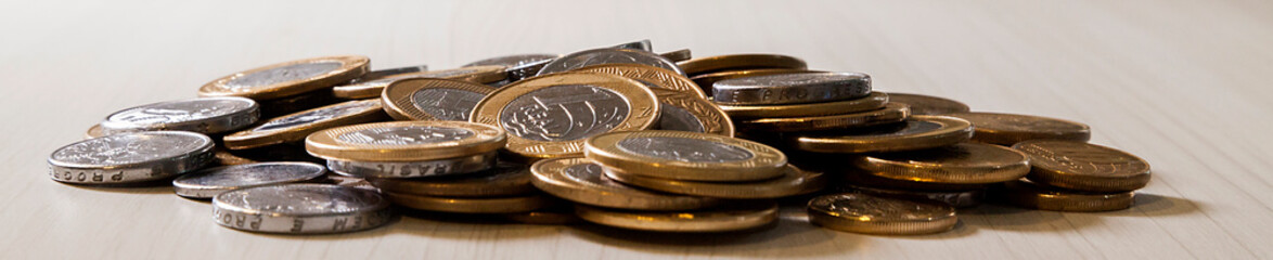 Pot with real currency, money from Brazil. Coins in the pot on the table. Brazilian economy, investments, income. Brazilian currency concept. Piggy bank concept.
