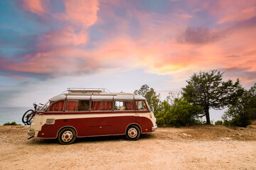 A red and white vintage van is parked on the seafront promenade in Sardinia during a stunning...