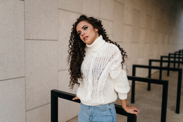 Fototapeta premium leaning behind her hands the black-haired curly-haired beauty with an attentive look looks tilting her head to the shoulder. High quality photo