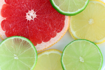 Colorful fruit slices including a grapefruit, lemon and lime on a white background.