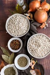 Traditional cuisine - raw beans and seasoning on wooden background