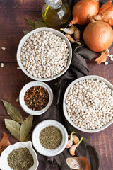 Traditional cuisine - raw beans and seasoning on wooden background