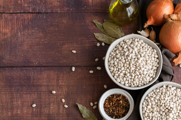 Traditional cuisine - raw beans and seasoning on wooden background