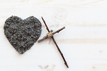 Wood cross with heart of ashes on white wood background with copy space
