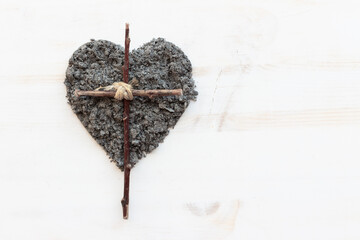 Wood cross with heart of ashes on white wood background with copy space